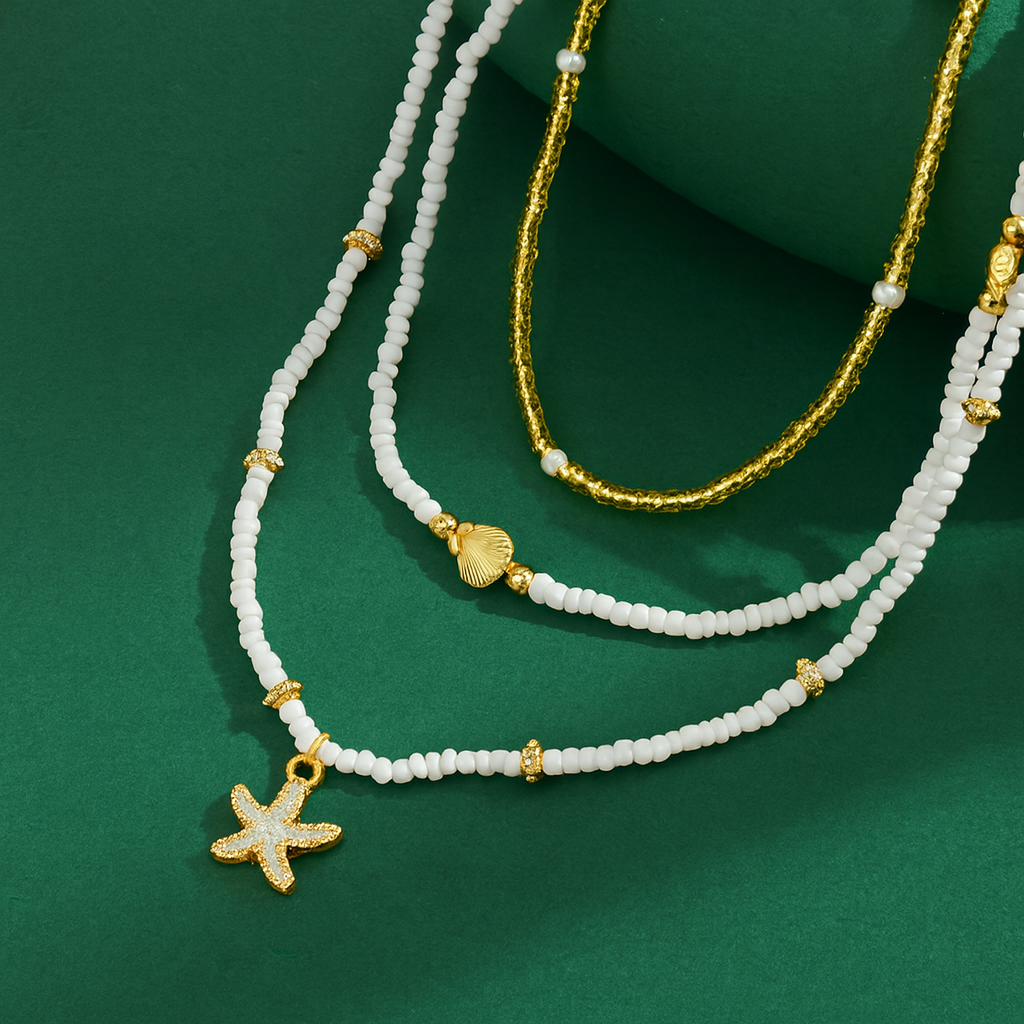 Three beaded necklaces with starfish charm on a green background