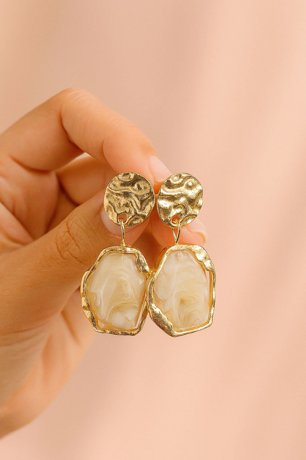 Textured gold drop earrings with cream marbled resin stones held in hand – Petal & Pine