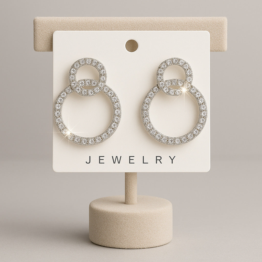 Pair of silver hoop earrings on a jewelry display card with a beige background