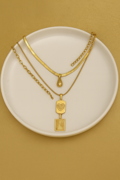 Gold necklaces on a white plate with a beige background