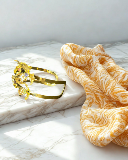 Opulence Bloom cuff bracelet with floral design in stainless steel, PVD gold plating, and colorful gemstone details On a marble