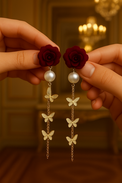 Earrings with red roses and pearl beads held by hands against a blurred background