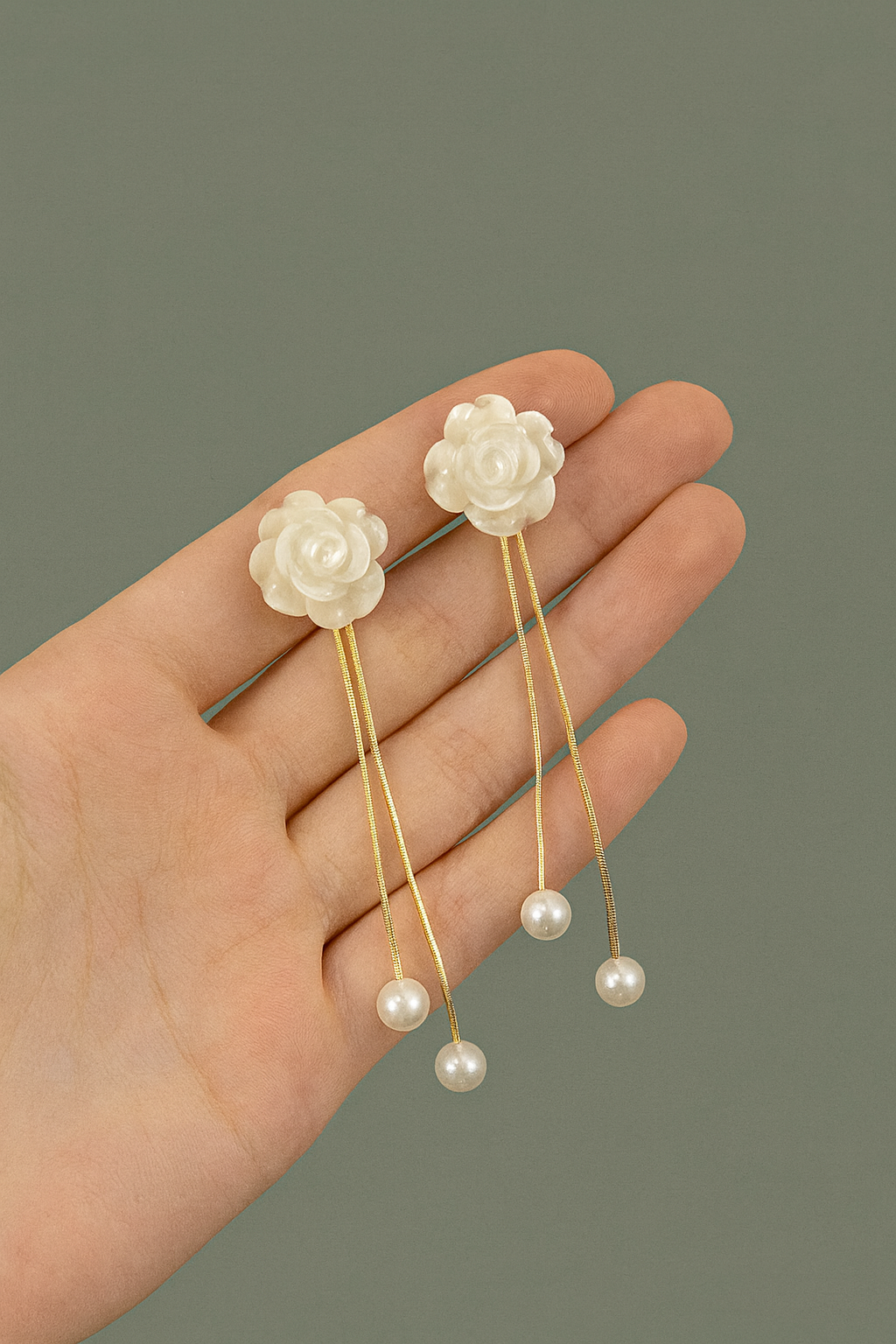 Hand holding a pair of floral hairpins with pearl details against a gray background