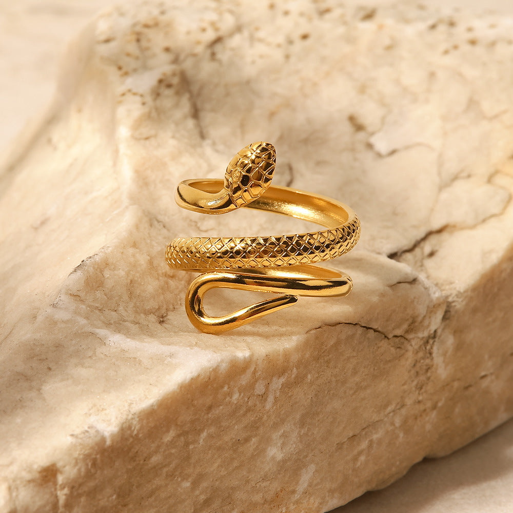 Serpentine Grace Ring – gold-plated stainless steel snake-inspired design placed on a marble